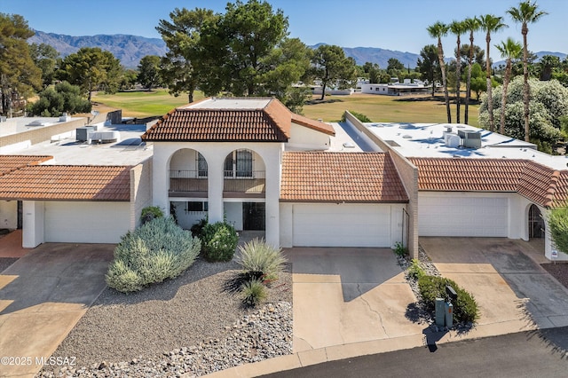 mediterranean / spanish home featuring driveway, a tile roof, and a mountain view