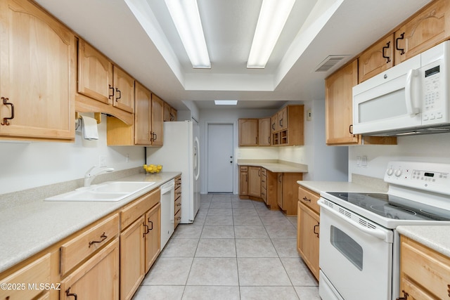 kitchen with light tile patterned floors, a raised ceiling, light countertops, a sink, and white appliances