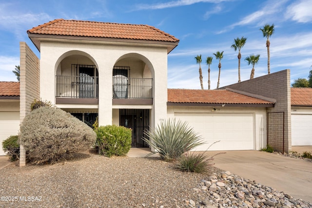 view of front of property featuring a tile roof, stucco siding, concrete driveway, a balcony, and a garage