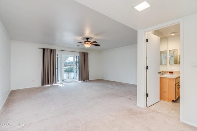 unfurnished room with light carpet, a ceiling fan, and a sink