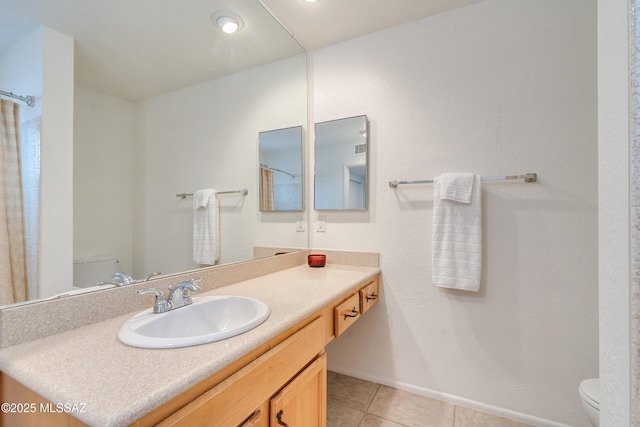 bathroom featuring toilet, vanity, baseboards, and tile patterned floors