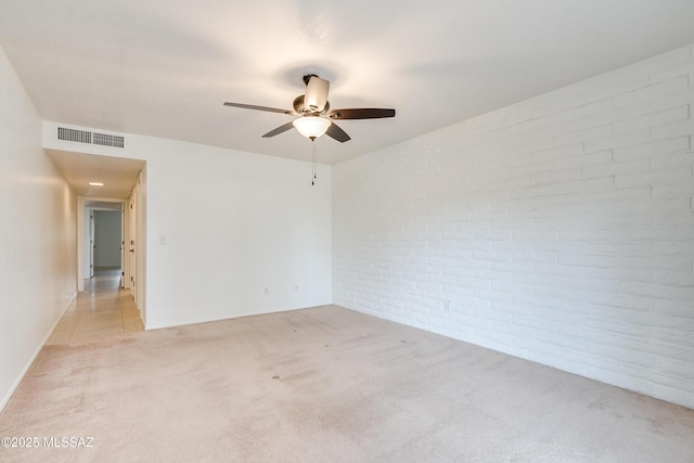 unfurnished room featuring brick wall, a ceiling fan, visible vents, and light colored carpet