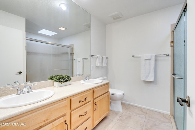 bathroom with a shower stall, double vanity, a sink, and tile patterned floors