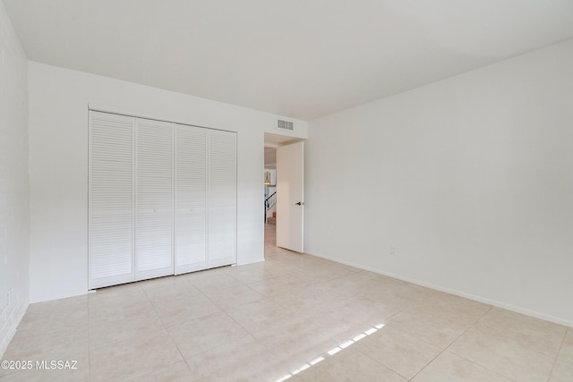 unfurnished bedroom with a closet, light tile patterned flooring, visible vents, and baseboards