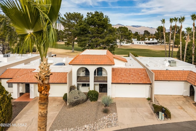 view of front facade with a mountain view, a garage, a tile roof, concrete driveway, and stucco siding