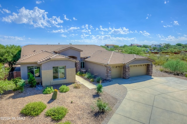 view of front of property featuring an attached garage, stone siding, stucco siding, concrete driveway, and a tiled roof