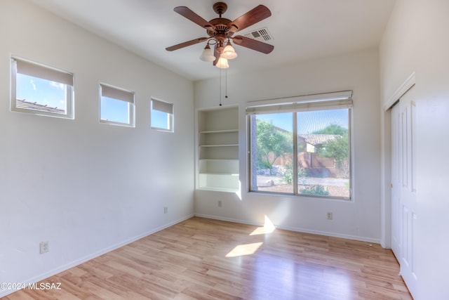 empty room featuring baseboards, a ceiling fan, light wood-style flooring, and visible vents