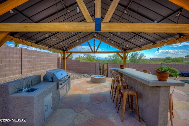 view of patio with grilling area, a sink, a gazebo, outdoor wet bar, and an outdoor kitchen