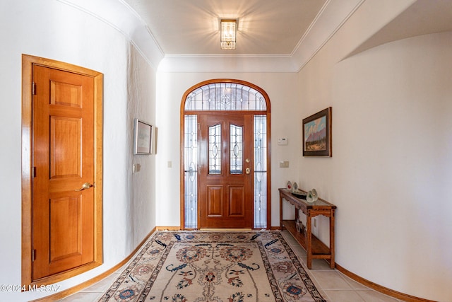 foyer with crown molding and light tile patterned floors