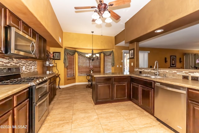 kitchen with appliances with stainless steel finishes, light tile patterned flooring, sink, decorative light fixtures, and decorative backsplash