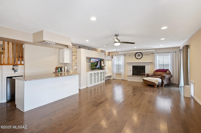 living room featuring a tiled fireplace, dark hardwood / wood-style floors, and ceiling fan