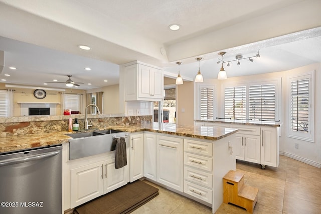 kitchen featuring dishwasher, sink, kitchen peninsula, and stone counters