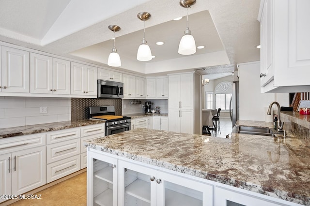 kitchen featuring a tray ceiling, decorative light fixtures, white cabinets, kitchen peninsula, and stainless steel appliances