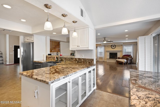 kitchen with decorative light fixtures, sink, white cabinets, kitchen peninsula, and stainless steel refrigerator with ice dispenser