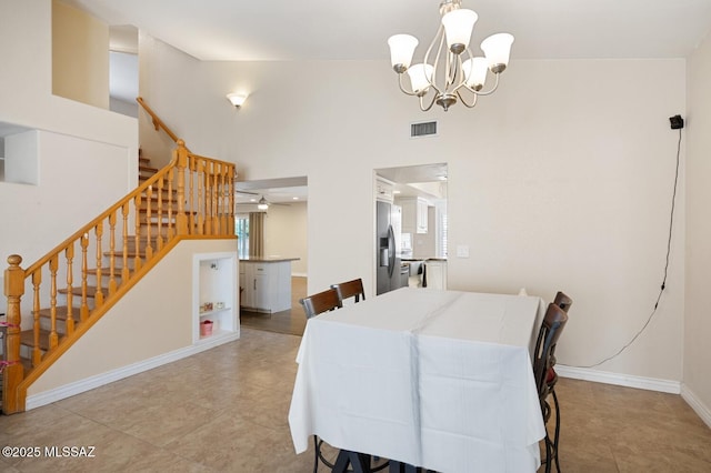 dining room with light tile patterned floors, a chandelier, and a high ceiling