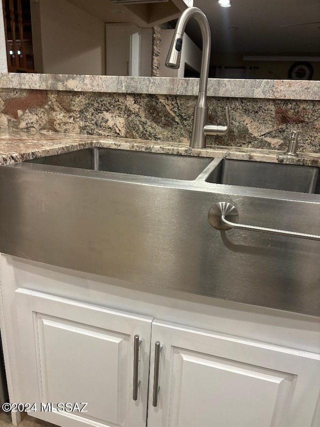 interior details featuring white cabinetry, sink, and dark stone countertops