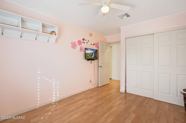 unfurnished bedroom featuring ornamental molding, a closet, and light wood-type flooring