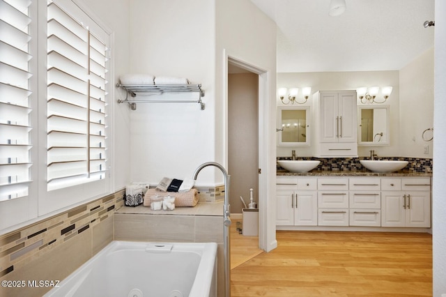 bathroom featuring hardwood / wood-style flooring, backsplash, a bathtub, vanity, and a chandelier