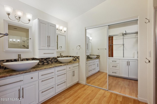 bathroom with lofted ceiling, vanity, hardwood / wood-style floors, and decorative backsplash