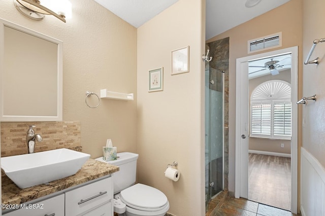 bathroom with ceiling fan, vanity, a shower with shower door, and backsplash