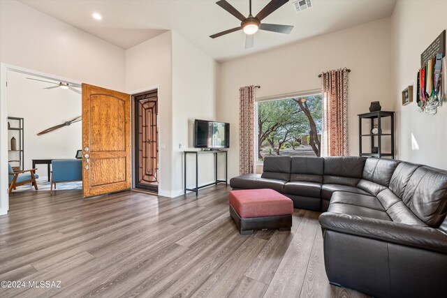 living room with hardwood / wood-style flooring, ceiling fan, and vaulted ceiling