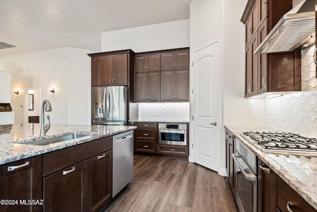 kitchen with backsplash, wall chimney exhaust hood, sink, and stainless steel appliances