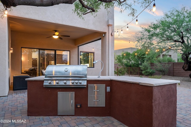 patio terrace at dusk featuring ceiling fan and area for grilling