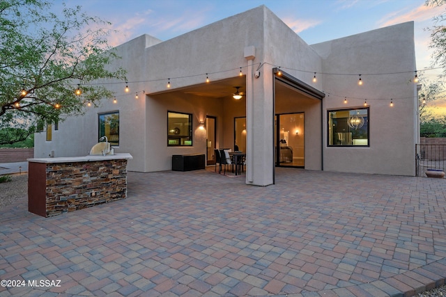 back house at dusk with exterior bar and a patio