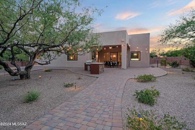 back house at dusk featuring a patio area