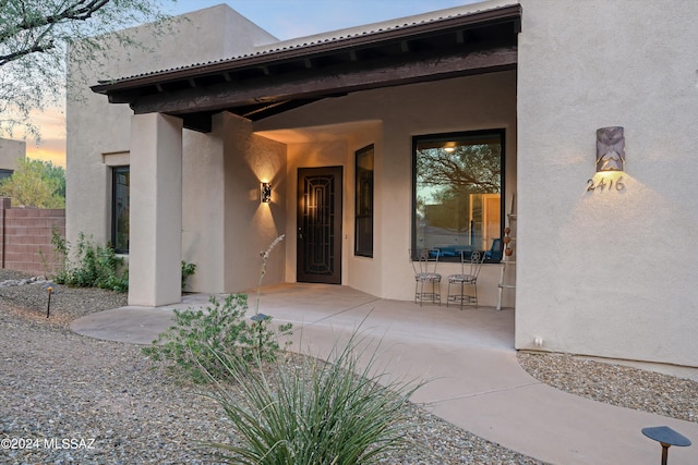 exterior entry at dusk featuring a patio area