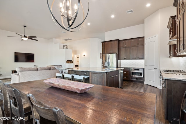 dining space with dark wood-type flooring and ceiling fan with notable chandelier