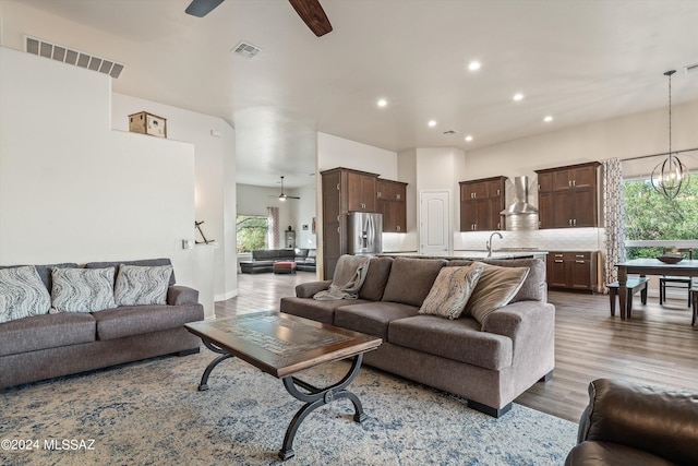 living room featuring hardwood / wood-style floors, ceiling fan with notable chandelier, a healthy amount of sunlight, and sink