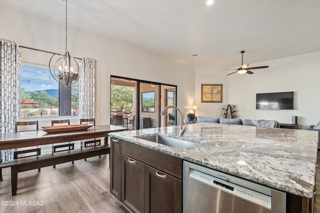 kitchen with light stone counters, dark brown cabinetry, dishwasher, and sink