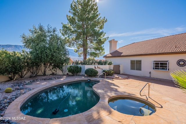 view of pool with an in ground hot tub, a mountain view, and a patio area