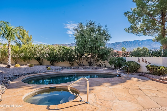 view of pool featuring a mountain view, a patio, and an in ground hot tub