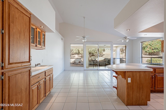 kitchen featuring a kitchen bar, tile counters, light tile patterned floors, and sink