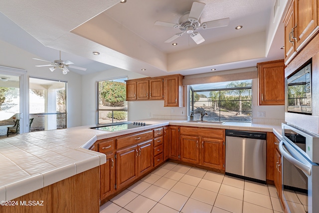 kitchen featuring appliances with stainless steel finishes, tile counters, a wealth of natural light, and sink