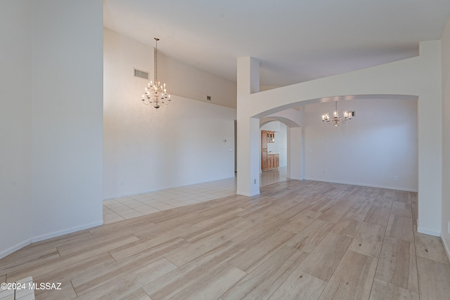 unfurnished room with a chandelier and light hardwood / wood-style floors