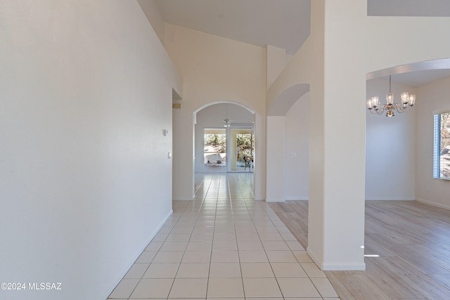 hallway featuring light hardwood / wood-style flooring, a chandelier, and a high ceiling