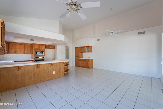 kitchen featuring a breakfast bar, high vaulted ceiling, sink, appliances with stainless steel finishes, and kitchen peninsula