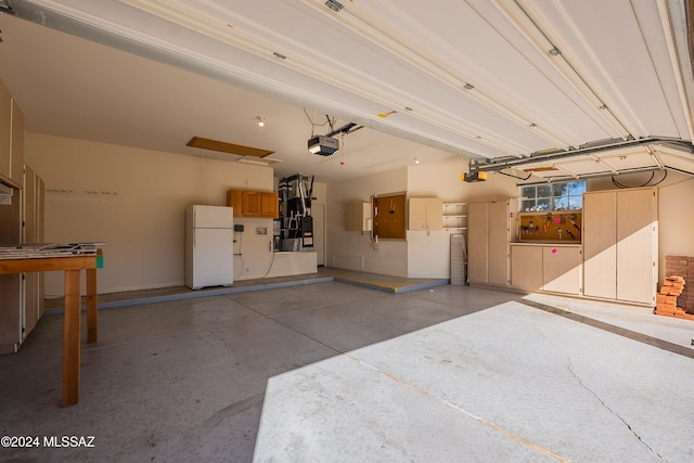 garage featuring white fridge and a garage door opener