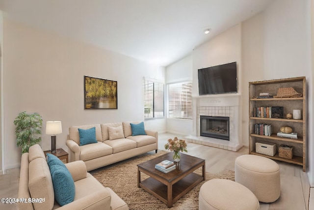 living room with high vaulted ceiling and a tiled fireplace