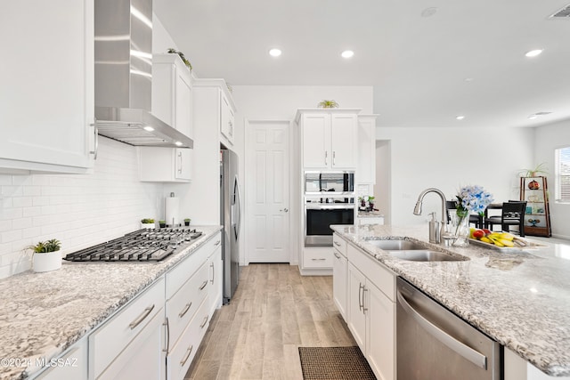 kitchen featuring white cabinets, appliances with stainless steel finishes, wall chimney exhaust hood, and sink