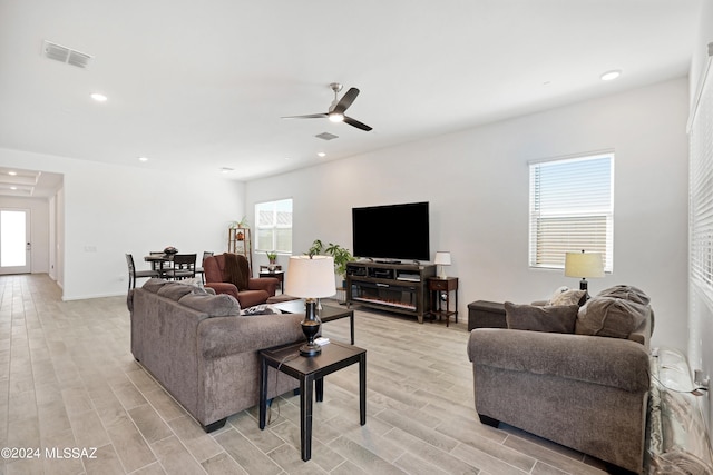 living room with ceiling fan, a wealth of natural light, and light hardwood / wood-style flooring