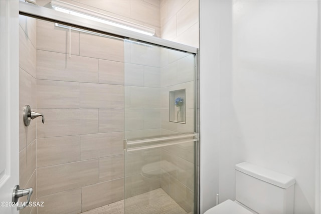 bathroom featuring toilet and a shower with door