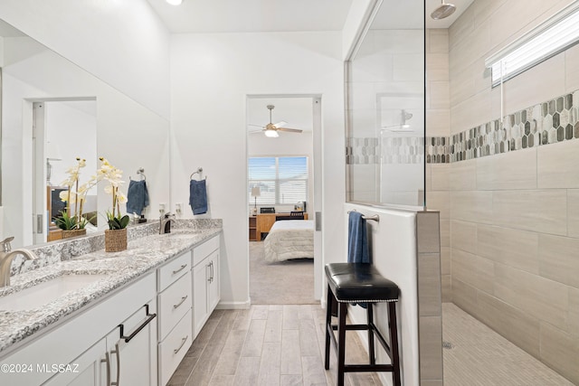 bathroom featuring ceiling fan, vanity, hardwood / wood-style floors, and tiled shower