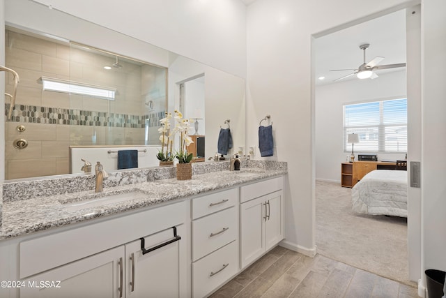 bathroom featuring a tile shower, hardwood / wood-style floors, vanity, and ceiling fan