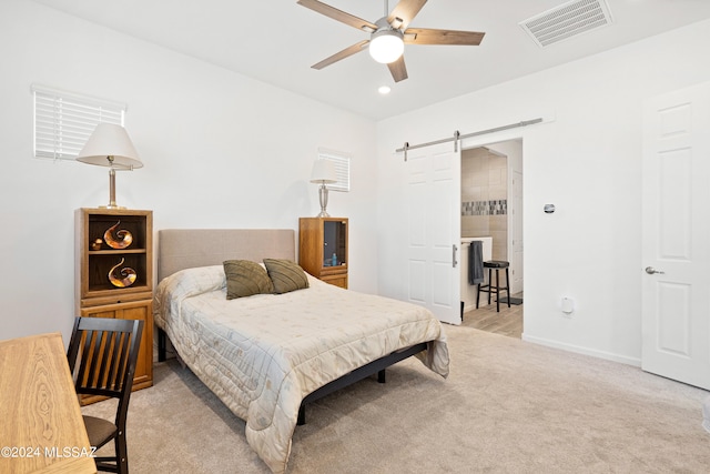 carpeted bedroom featuring ceiling fan and a barn door