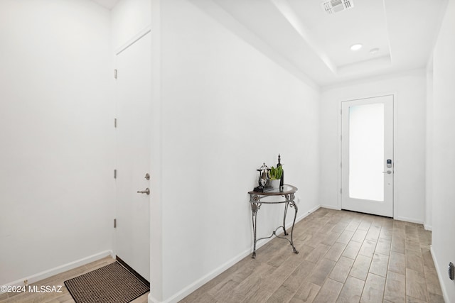 foyer entrance with light wood-type flooring and a tray ceiling