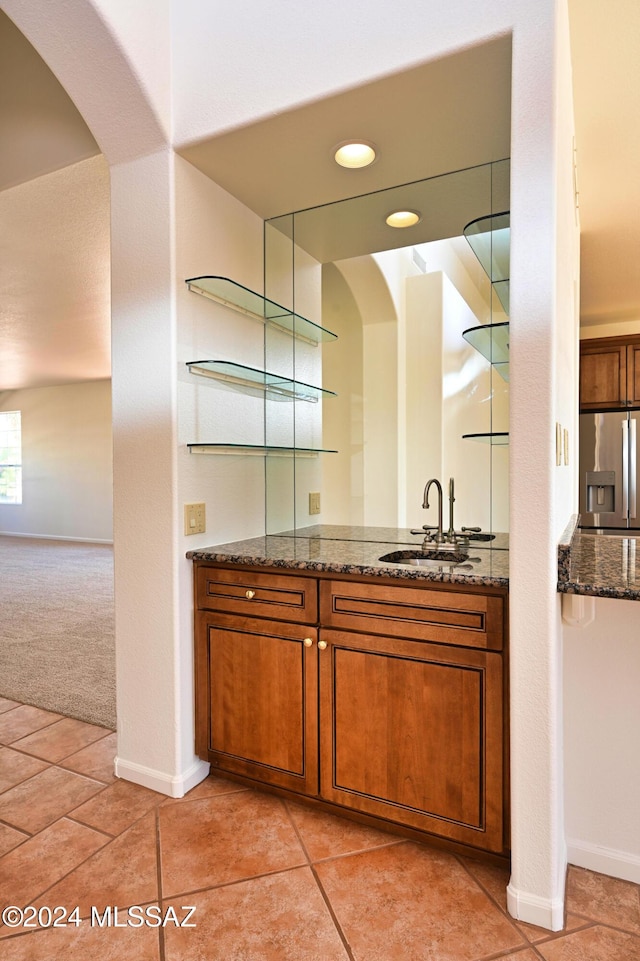 bar featuring baseboards, a sink, arched walkways, and stainless steel fridge with ice dispenser